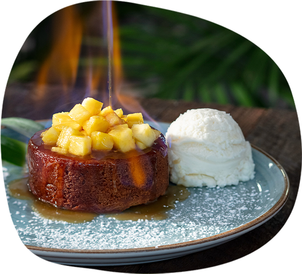 Flaming Pineapple Butter Cake topped with fresh pineapple, salted rum caramel, and vanilla ice cream