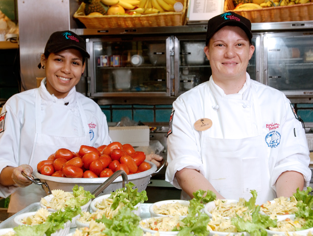Two Bahama Breeze Chefs smile as they prepare food